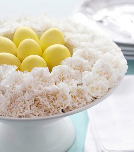 I love this gorgeous Easter floral centerpiece: a flower "nest" with white carnations and yellow dyed Easter eggs.  So simple and so beautiful! Easter decor - spring decorating ideas - easter centerpiece - easter tablebeautiful floral "nest" filled with Easter eggs #easterdecorations