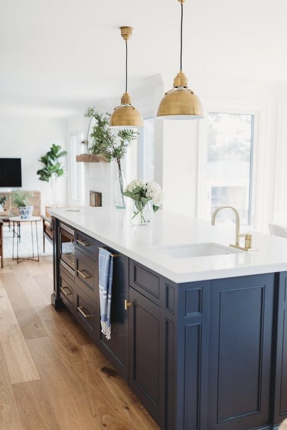 Blue and white kitchen with brass pendant lighting over island by Andrea McQueen Design