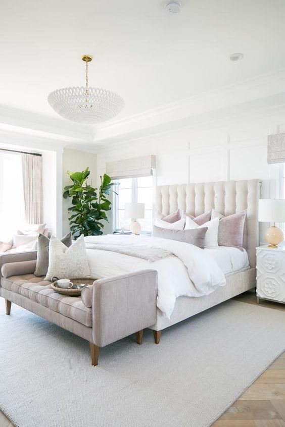 Love this beautiful transitional bedroom design with an upholstered bed and bench, white chandelier, and neutral bedding, decor, and furniture - design works home 