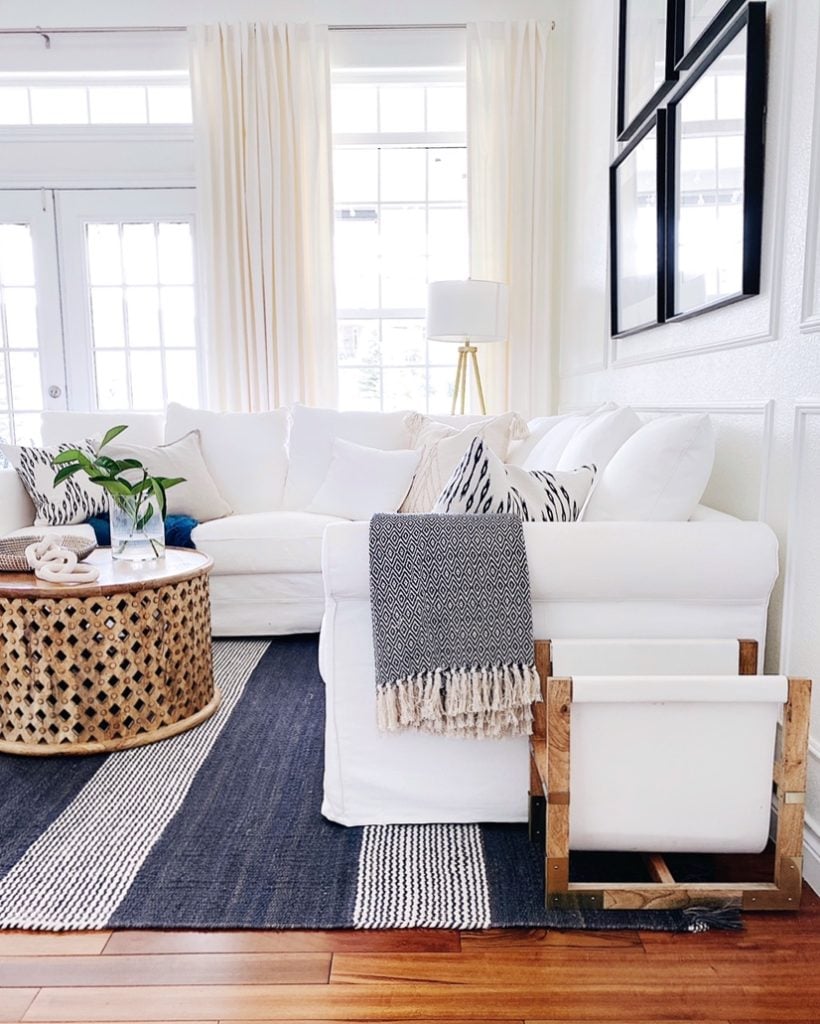 Neutral living room decor with striped rug, slipcovered sectional sofa, round coffee table and neutral pillows with a modern coastal touch - jane at home #decor #design #style #ideas