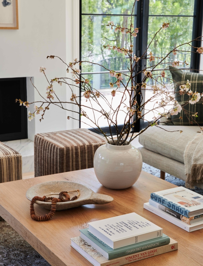 Beautiful warm coffee table styling with stacks of books and oversized branches in a glazed pot 