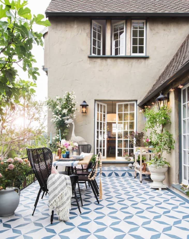 Beautiful patio with its blue and white geometric tile and outdoor dining space has a European farmhouse look