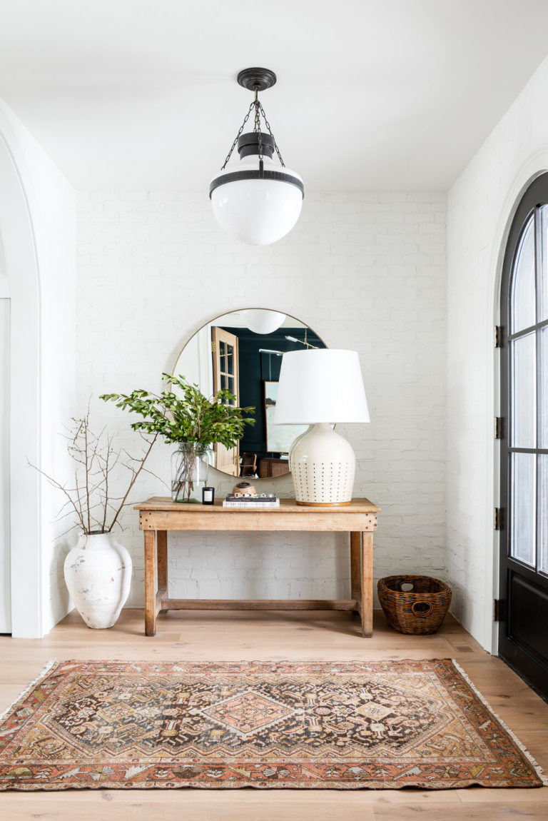 Beautiful modern entryway with round mirror, rustic console table and vintage rug - Studio McGee