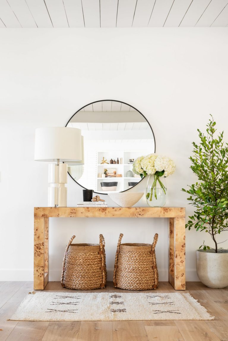 Beautiful entryway with modern console table, baskets, and round mirror 