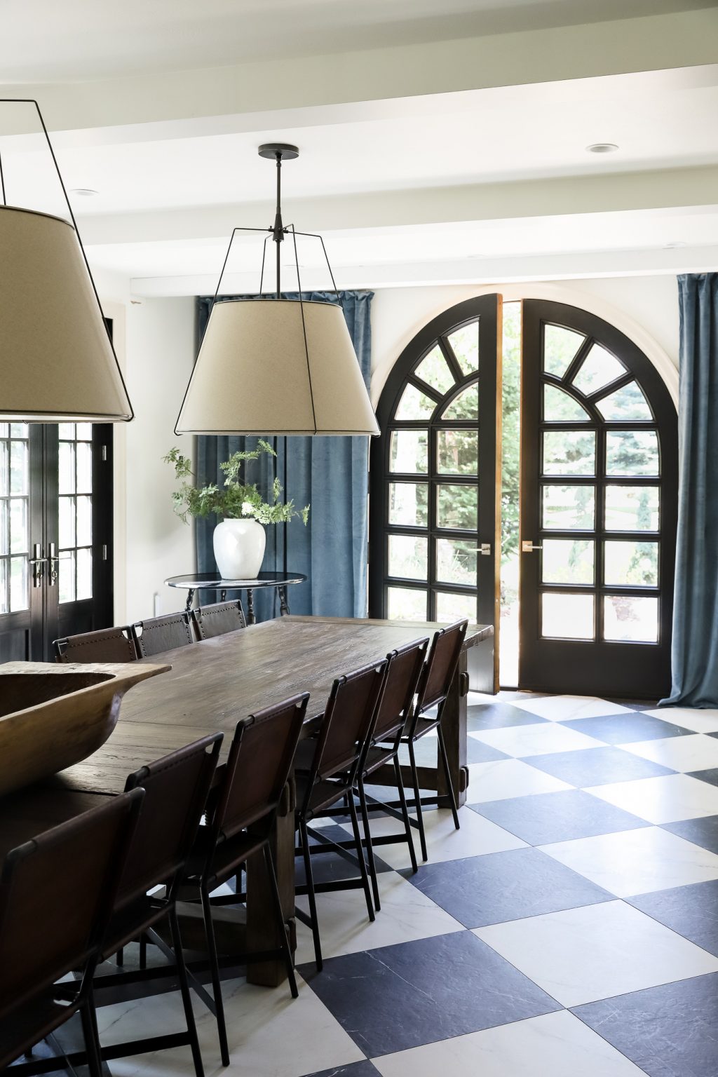 European style dining room with black and white tiled floor and arched wood doorway from Chris Loves Julia #diningroom #diningroomdecor #diningroomideas