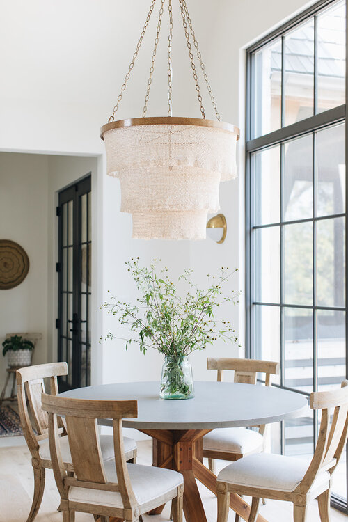 Love this beautiful kitchen dining area with a round wood table, wood dining chairs, and a tiered chandelier - quiet luxury - kate marker interiors