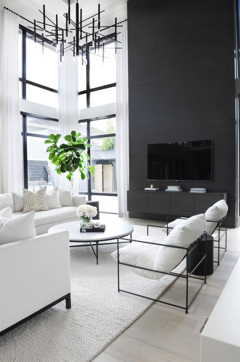 Love this beautiful transitional living room with a black fireplace surround and tv wall, vaulted ceilings, marble coffee table and white furniture - peridot