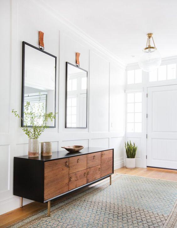 Love this beautiful contemporary entryway design with a large wood credenza and two mirrors - amber interior design