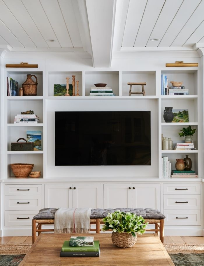 Living room with built in shelves and cabinets around TV and shiplap ceilings - Amber Interiors