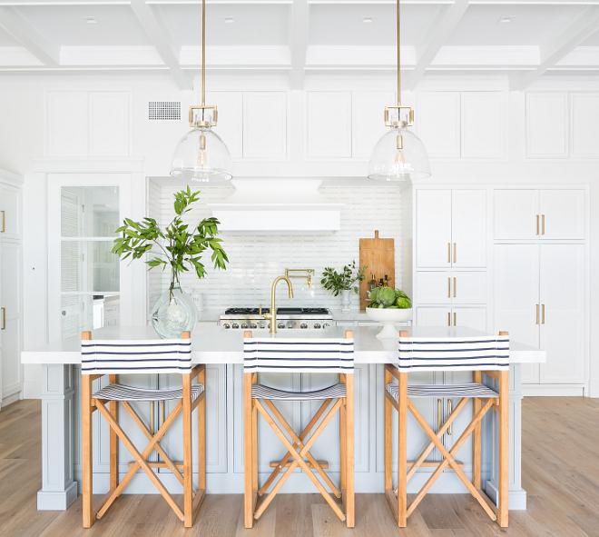 Beautiful modern coastal kitchen with light blue gray island and striped counter stools