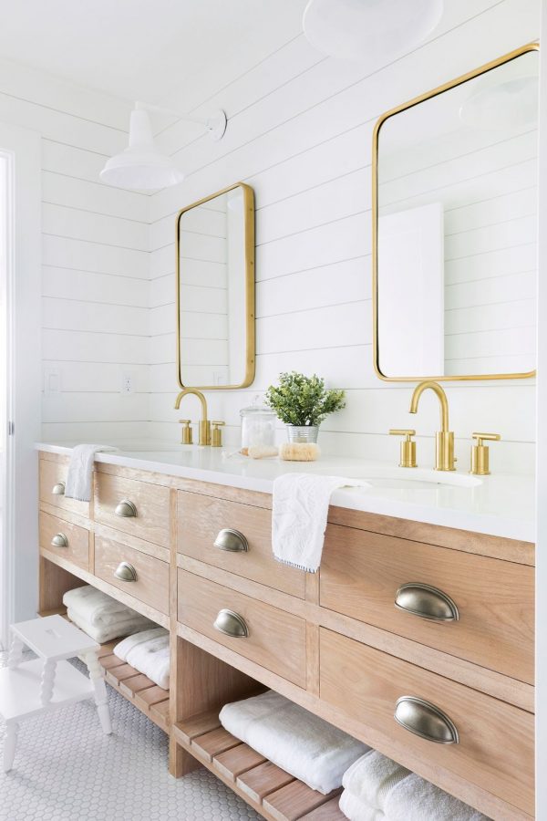 Love this beautiful bathroom design with a light wood vanity, brass mirrors and faucets, and nickel cabinet hardware