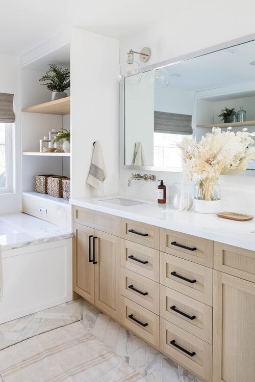 Modern bathroom with light wood vanity and built in tub and shelving