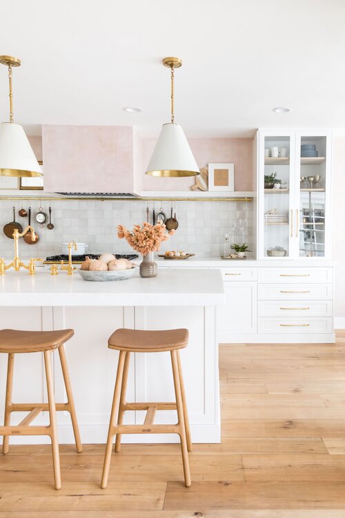 Love this beautiful kitchen design with zellige tile backsplash, white kitchen cabinets, modern cone pendant lights, and a touch of blush on the range hood and upper walls - kitchen cabinet ideas - kitchen cabinet colors - beach house interior design - gorgeous kitchens - timeless kitchen - pure salt interiors