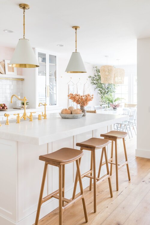 Beautiful modern white kitchen with cone pendant lights and wood counter stools.