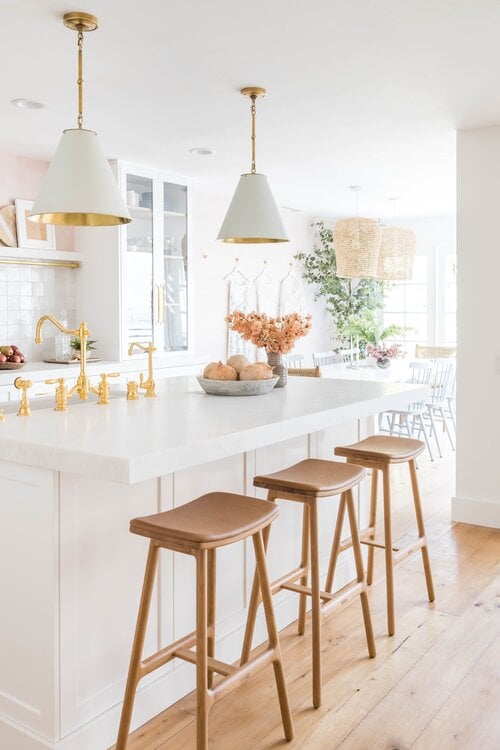 Beautiful all white kitchen with cone pendant lights and extra thick countertop on island