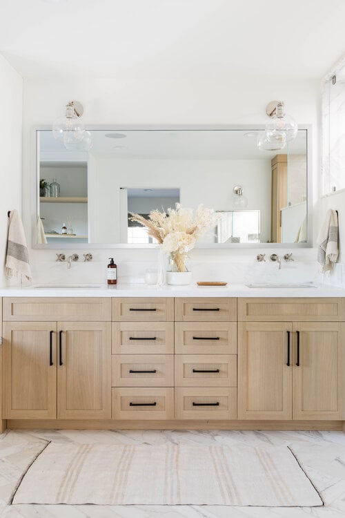 Love this beautiful modern master bathroom design with a light oak wood vanity, black hardware, and chrome faucets and sconces - bathroom ideas - bathroom decor - bathroom cabinet ideas - coastal bathrooms - beach house interior design - pure salt