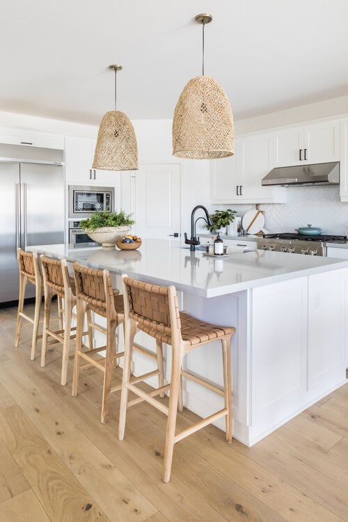 Beautiful beach house kitchen with woven stools and pendant lights over the island