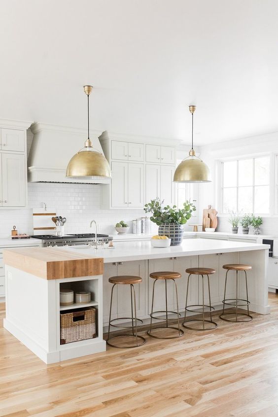 Beautiful all white kitchen with butcher block countertop on island and brass pendant lights