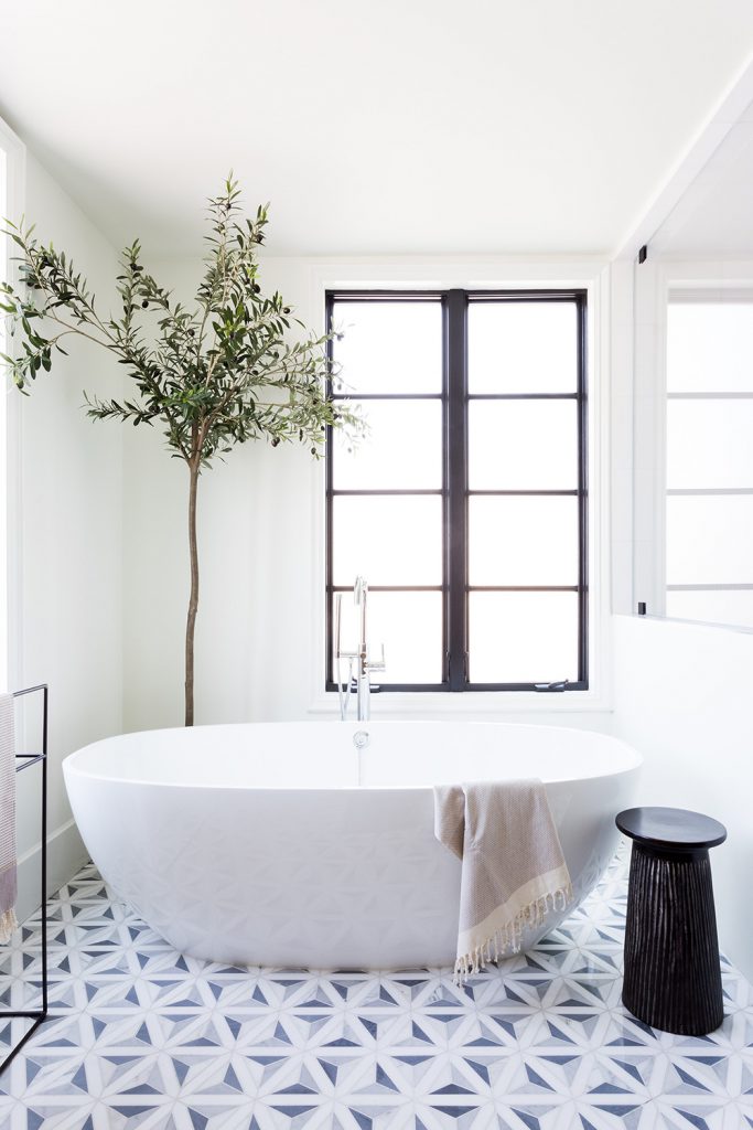 The patterned tile flooring in this bathroom takes it a notch above the ordinary, and the olive tree adds such a lovely touch of life to this pretty bathroom!