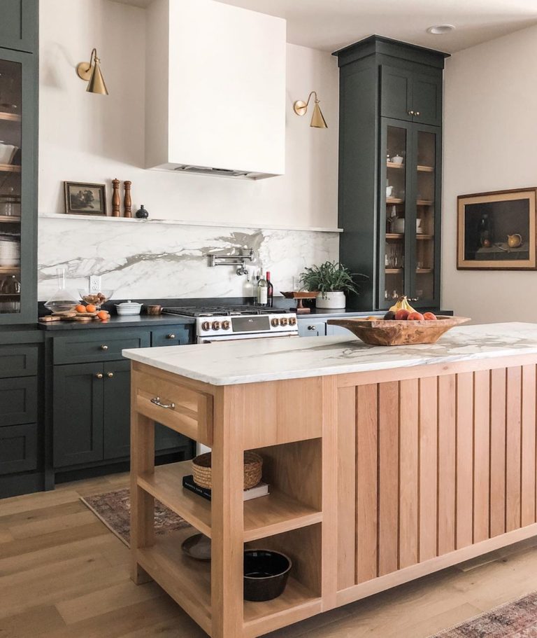 Such a warm and wonderful kitchen! I love the light wood island and dark green cabinets, paired with the touches of brass in the sconces. And that marble backsplash is amazing!! kitchen island and dark kitchen cabinets - Kelsey Leigh Design