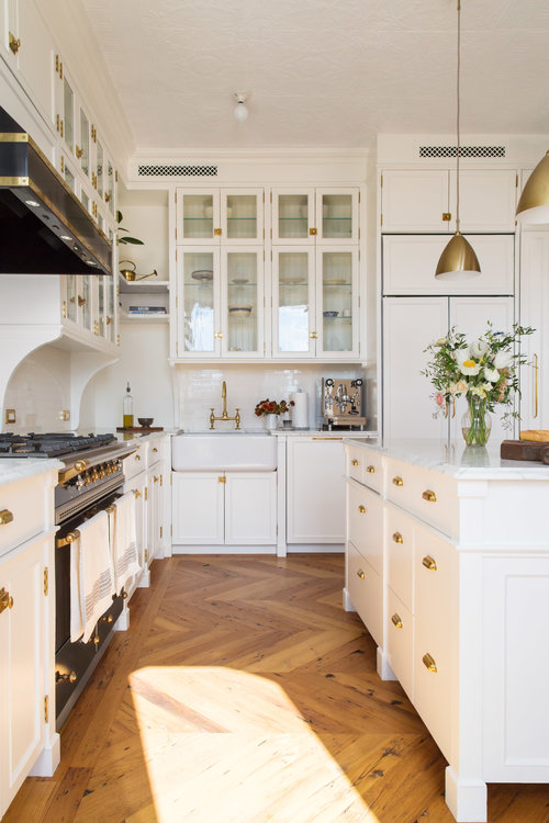 This kitchen has so many wonderful elements, I don't know where to begin!  The gorgeous mix of white cabinets, black stove and vent hood, light wood herringbone flooring, and gold and brass lighting and hardware are absolutely breathtaking! kitchen remodel - kitchen design - kitchen decor - white kitchen - kitchen ideas