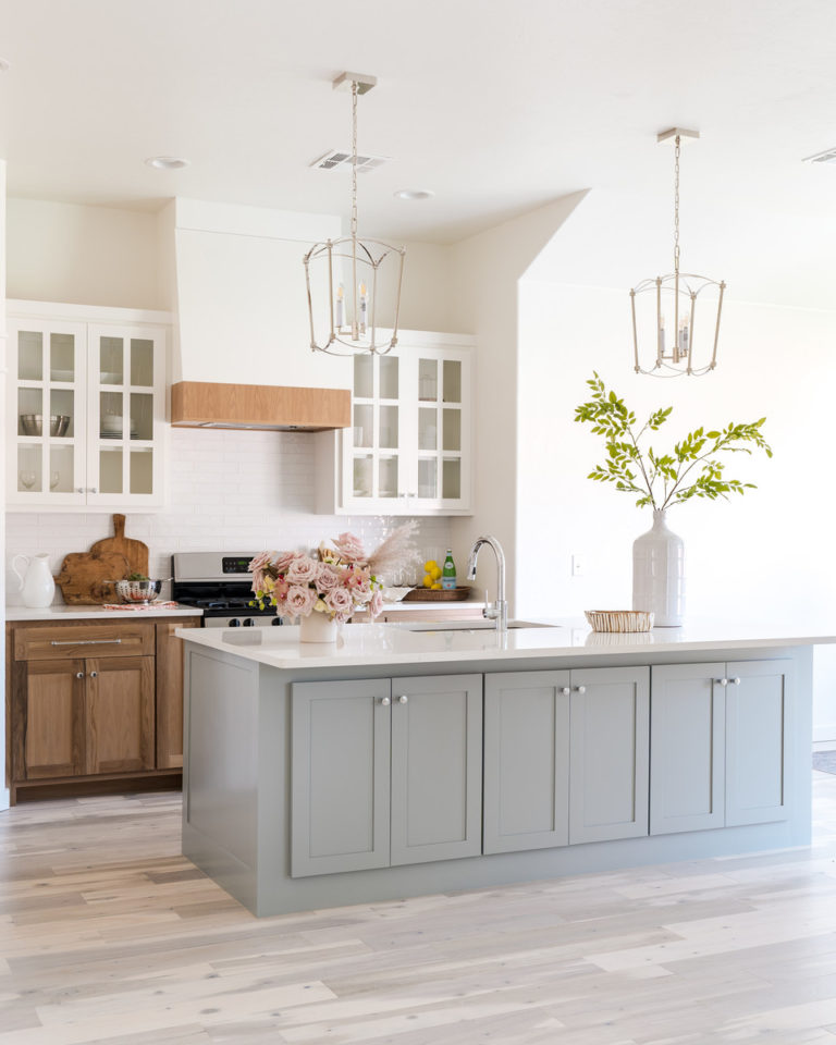 This beautiful kitchen, with its mix of light gray blue island, white upper cabinets, and rustic wood lower cabinets, exudes springtime! kitchen remodel - kitchen ideas - white kitchen - kitchen lighting ideas - kitchen island ideas