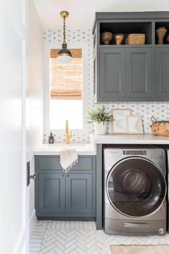 I love everything about this beautiful laundry room! The wallpaper, cabinet color, herringbone tile flooring, and lighting are all so pretty! laundry room ideas - laundry room design - laundry room decor
