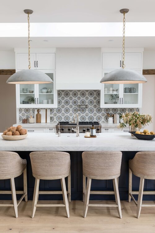 Beautiful modern kitchen design with patterned tile backsplash, black pendant lights, dark island color, and woven counter stools - kitchen design - kitchen decor - coastal kitchen