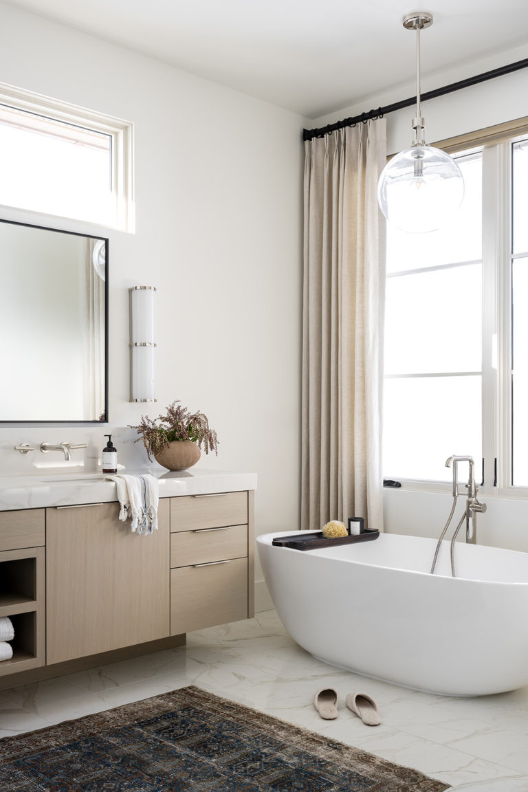 Beautiful modern master bathroom with light wood vanity and freestanding tub