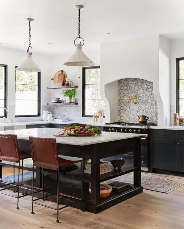 Urban kitchen design with dark lower cabinets and island and patterned tile backsplash over stove 