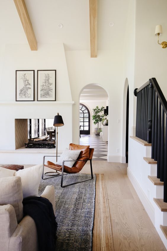 Beautiful modern living room design with white walls, wood beams, see through fireplace and arched doorway - chris loves julia - living room ideas - transitional living room