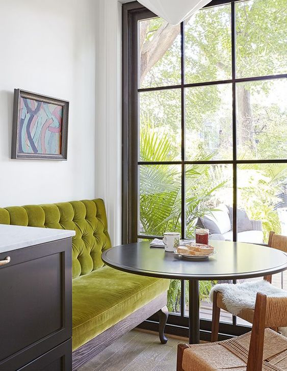 Beautiful breakfast nook with green velvet banquette seating and black framed window - House and Home