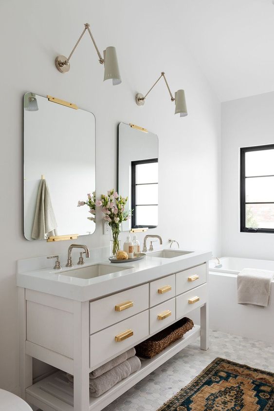 Modern bathroom vanity, hexagonal gray and white tile, sconces, vintage Turkish rug, gold mirrors and pulls, tub