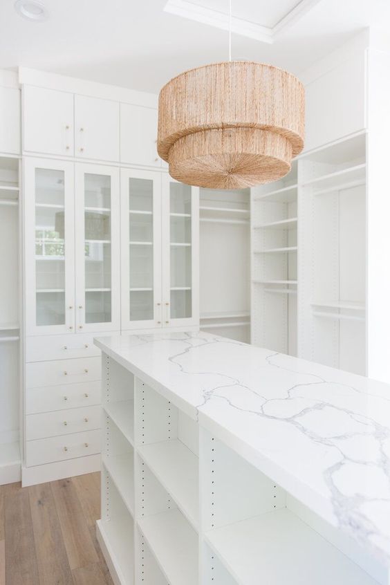 Stunning master closet with built in cabinets and shelves, island, marble top, and woven pendant light - the life styled co. - interior design 
