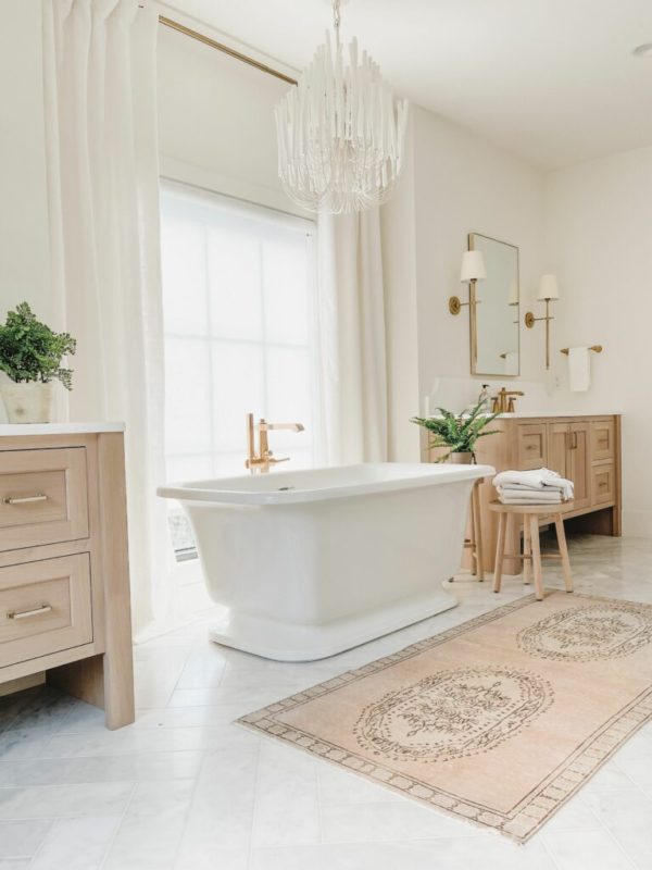 Love this beautiful master bathroom with two light oak wood vanity cabinets, a freestanding tub, and vintage rug - bathroom remodel - bathroom ideas - bathroom decor - alexis andra austin