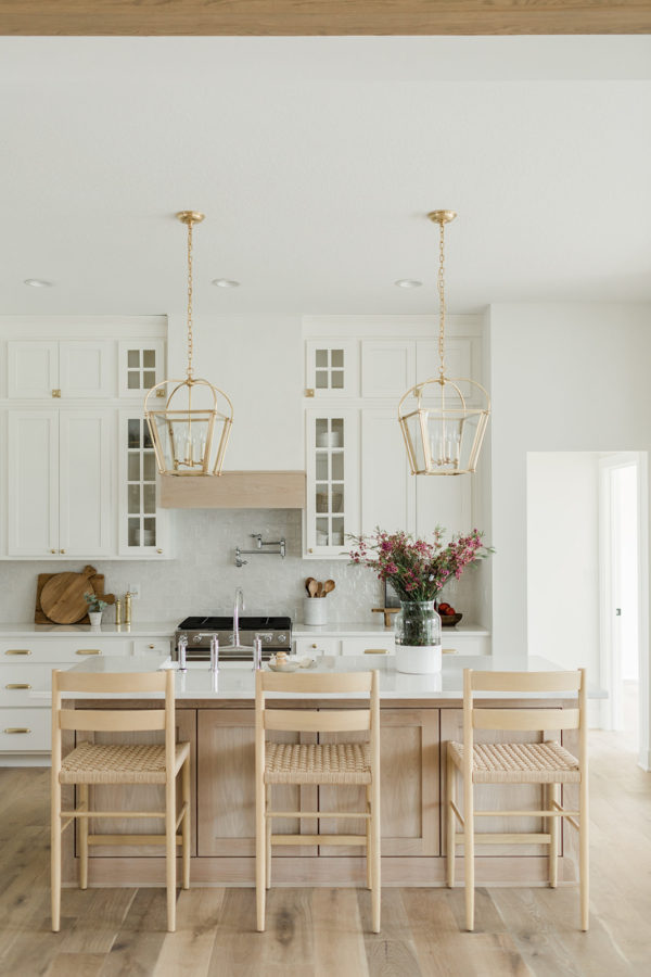 Love this beautiful European style kitchen design with a light oak wood island, woven counter stools, white cabinets, and brass pendant lights - kitchen ideas - kitchen decor - kitchen island ideas - kitchen lighting - kitchen cabinet ideas