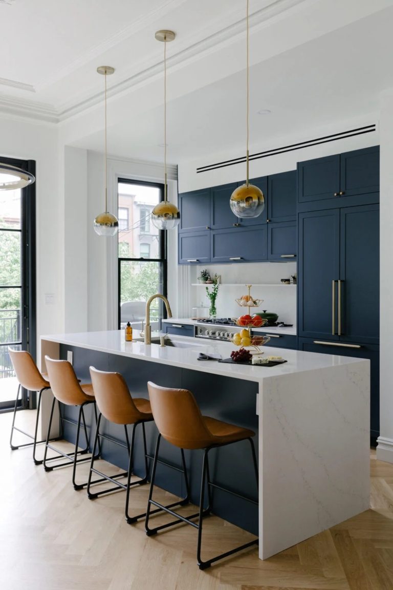 Beautiful navy blue kitchen with white waterfall countertop on the island