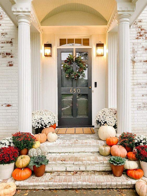 Love this beautiful modern fall front porch idea with a mix of colorful pumpkins, flowers, and more - bless'er house - fall porch ideas - fall stoop - front porch - autumn - fall porch decor 