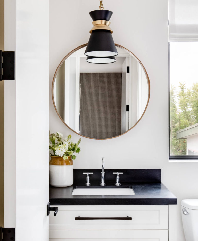 Love this striking small bathroom design - the round mirror, mix of metals, black and white, and pendant light give this space a modern coastal touch - lindye galloway