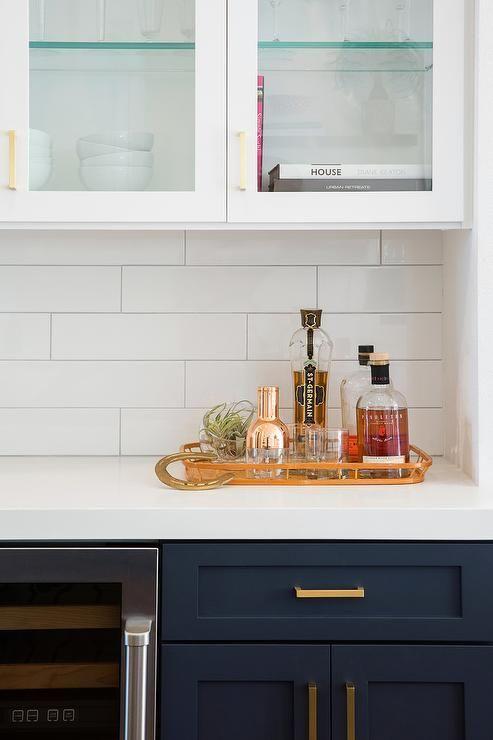 Love this beautiful timeless kitchen design with a white subway tile backsplash, white upper cabinets, and dark navy blue lower cabinets - studio surface design
