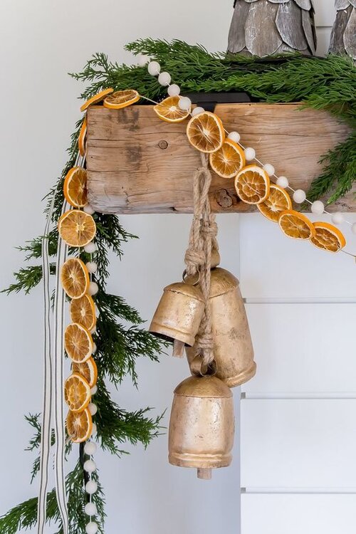 Love this rustic holiday mantel decorated with dried orange slice, wood and cypress garlands and brass bells - House of Jade - Christmas decor - holiday decor - Christmas mantel - mantle decor