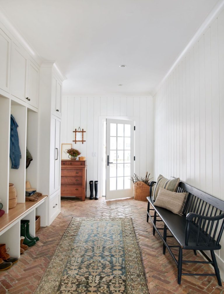 Love this beautiful entryway and mudroom with a modern bench, rug, and built in shelves - amber interiors