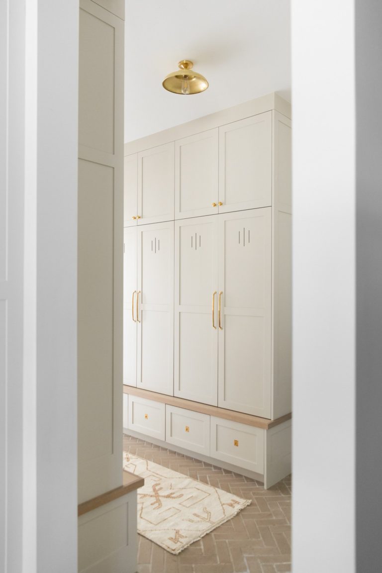 Love this beautiful mudroom design with floor to ceiling white cabinets and brass gold accents - ames interiors