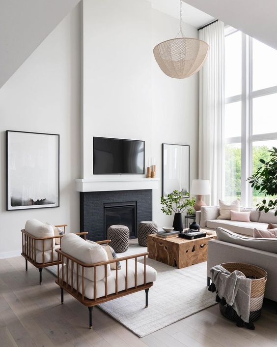 Love this beautiful modern living room design with a wood plinth style coffee table, fireplace, tv wall, tall windows and ceilings, neutral decor and furniture, and chandelier - le clair decor