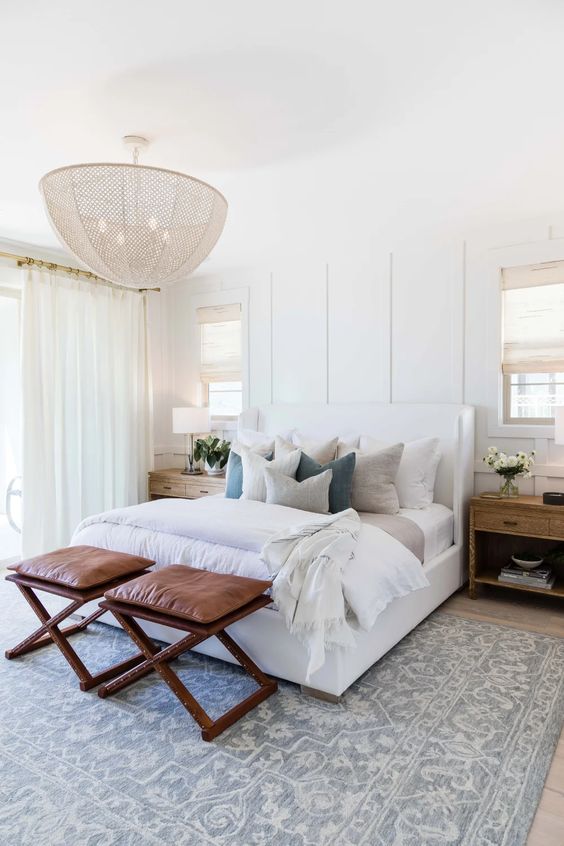 Love this beautiful modern master bedroom with neutral bedding and furniture, a statement chandelier, and two leather stools at the end of the bed - bedroom decor - modern bedroom ideas - coastal bedroom - luxury bedroom