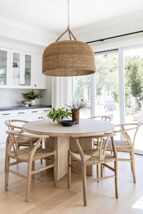 Love this beautiful modern kitchen dining area and breakfast nook with a round wood dining table, wood wishbone style dining chairs, and a large woven pendant light over the table - pure salt interiors