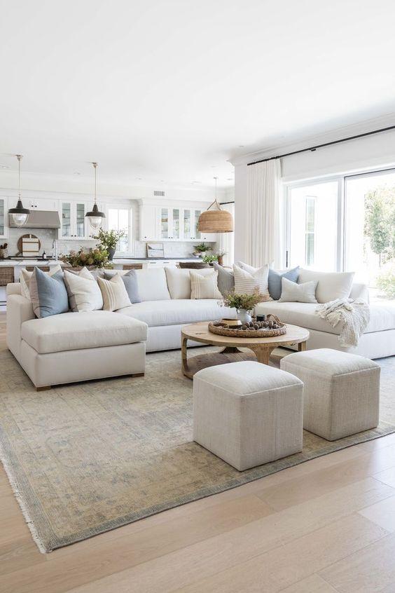 Love this beautiful modern living room design with a large neutral sectional, a round wood coffee table, and two square ottomans - living room ideas - living room decor - living room table - living room furniture ideas - coastal style - coastal interiors