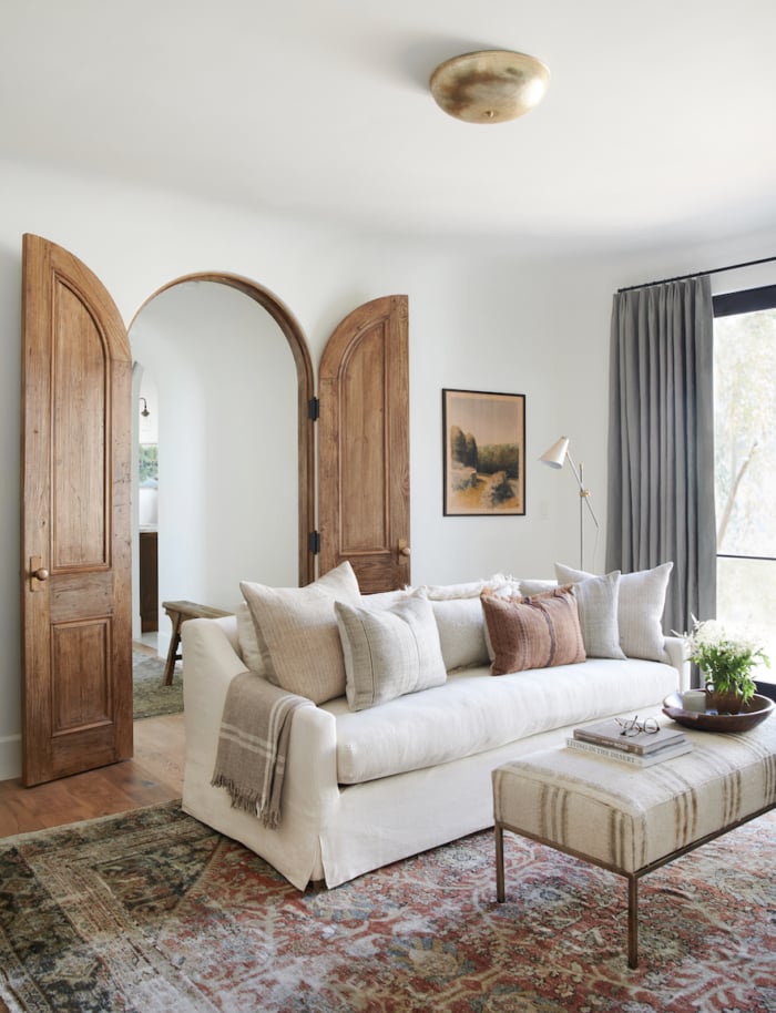 Beautiful modern farmhouse living room with white linen slipcovered sofa, arched doorway, and earth toned rug - living room ideas - living room decor 