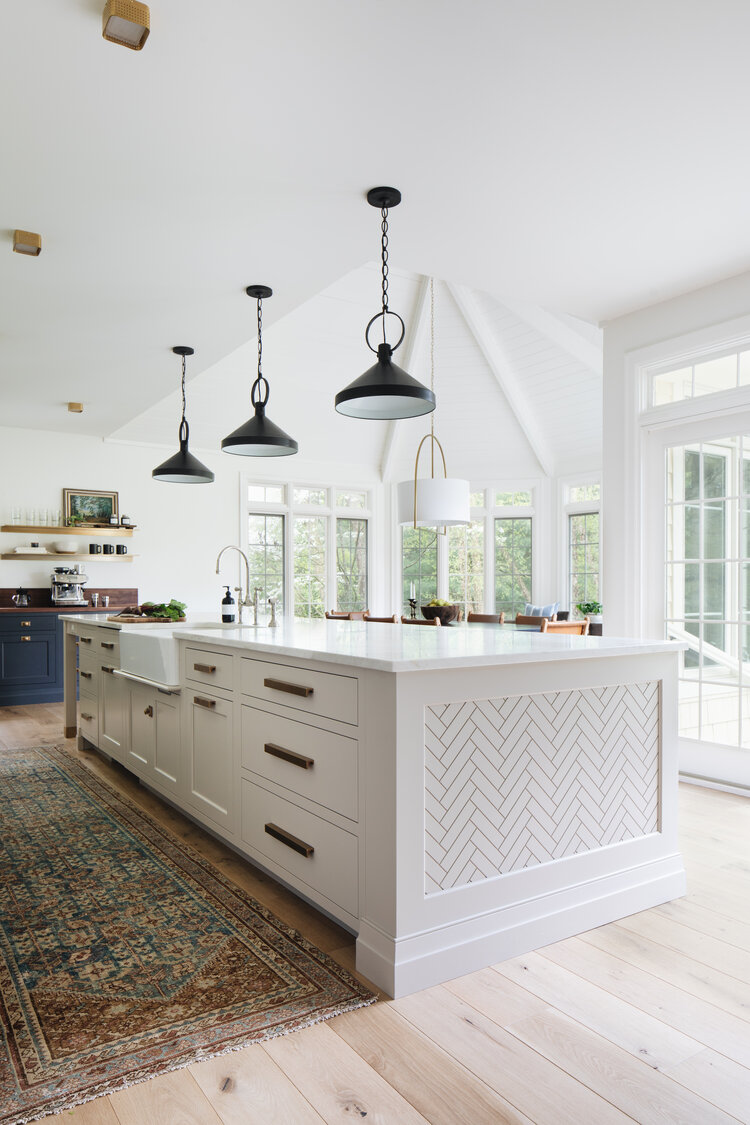 Beautiful modern kitchen design with white cabinets, black pendant lights, and herringbone pattern on the kitchen island 