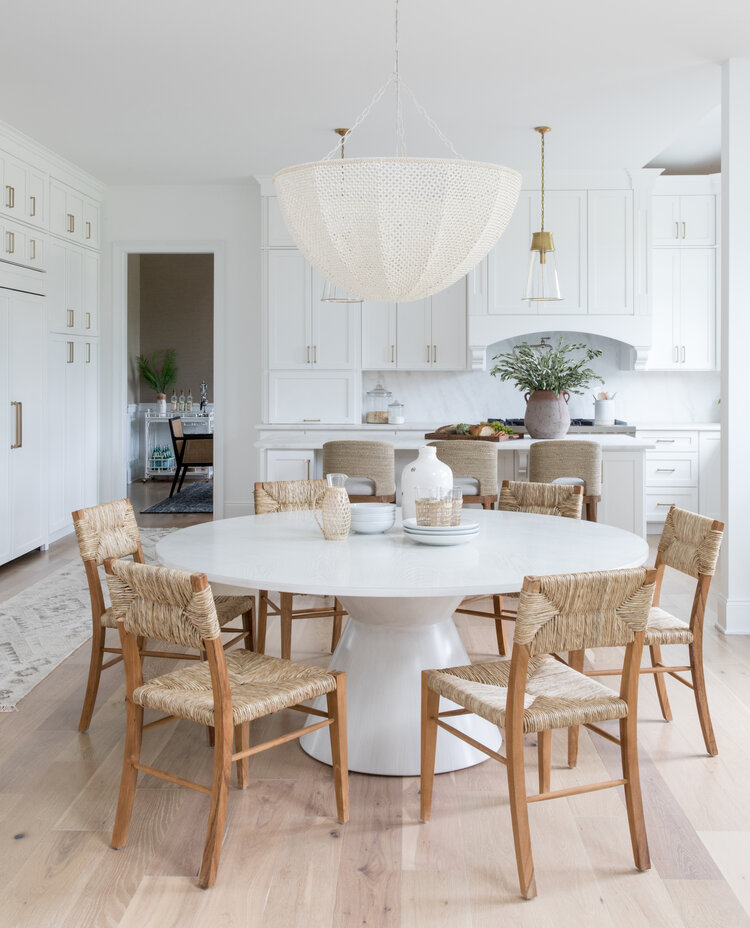 Love this beautiful kitchen dining area with a white dining table, wood and woven dining chairs and a woven white chandelier - salt design co.